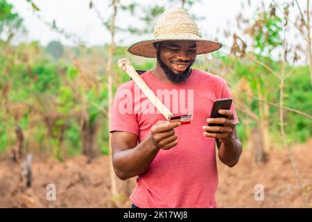 agriculteur africain utilisant son téléphone et sa carte de crédit Banque D'Images