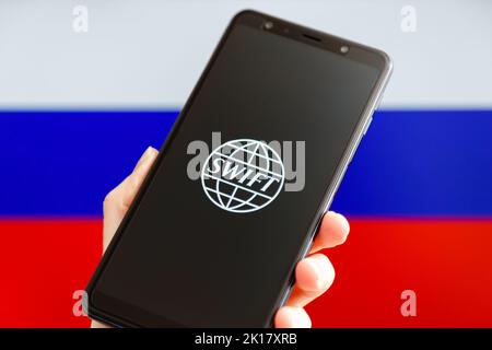 Ukraine, Kiev - février 23 2022 : portable avec logo SWIFT et drapeau russe en arrière-plan. Sanctions contre la Russie, déconnexion du concept SWIFT. Banque D'Images