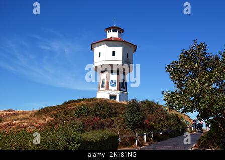 Un phare au sommet d'une colline sous un ciel bleu clair Banque D'Images