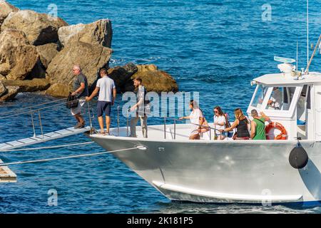 Groupe de touristes descendre d'un petit Ferry dans le petit port de l'ancien village de Tellaro, Lerici, Golfe de la Spezia, Ligurie, Italie. Banque D'Images