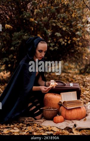 Une jeune femme dans les bois pratique la magie d'Halloween Banque D'Images