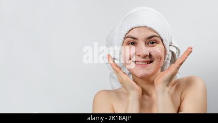 Une jeune femme souriante avec un masque naturel ou un ubtan sur son visage et une serviette blanche sur sa tête, un lieu de texte, un espace de copie Banque D'Images