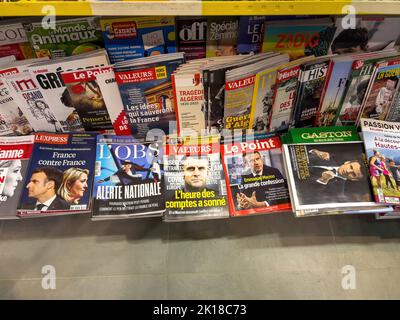 Paris, France - 17 avril 2022: POV main masculin tenant dans un kiosque de presse le dernier numéro de l'Express, l'OBS, Valeurs, le point, Gaston magazines journaux présentant Emmanuel Macron candidat à la présidence française Banque D'Images