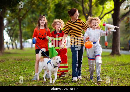 Les enfants se déguent en costume d'Halloween. Les enfants de couleur s'habillent avec un seau à bonbons dans la rue de banlieue. Petit garçon et fille trick ou traitement Banque D'Images