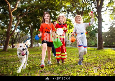 Les enfants se déguent en costume d'Halloween. Les enfants de couleur s'habillent avec un seau à bonbons dans la rue de banlieue. Petit garçon et fille trick ou traitement Banque D'Images