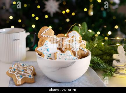 biscuits au pain d'épice dans un bol blanc sur fond de lumières de noël Banque D'Images