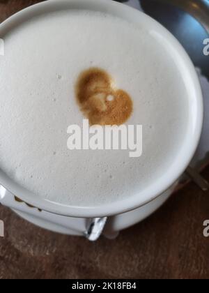 Tasse de café latte en forme de coeur et grains de café sur fond de bois ancien Banque D'Images