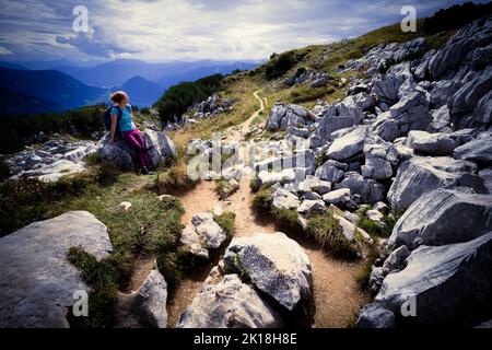 Vue d'un randonneur femelle reposant sur le précipice près du pic du perdant, entouré de rochers proéminents qui ont l'air travaillé, Ausseer Land, Styrie, Autriche Banque D'Images