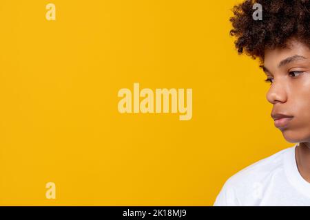 Les vies noires comptent. Tolérance ethnique. Portrait de profil de jeune homme africain contrarié isolé sur l'espace de copie orange. Sentiments d'adolescent. Émotion mélancolique. Banque D'Images