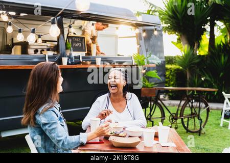 Heureux multiracial senior amis ayant plaisir à manger dans un marché de camion de nourriture de rue Banque D'Images