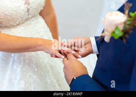 Marié mettant un anneau de mariage sur le doigt de la mariée, cérémonie de mariage, isolé Banque D'Images