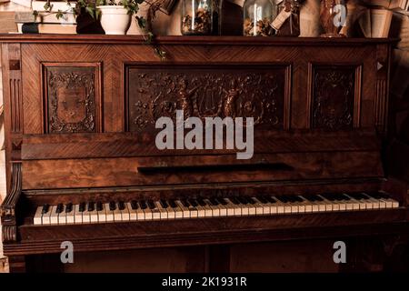 Un vieux piano dans une pièce sombre. Beaucoup de livres sur les murs Banque D'Images