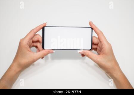 belles mains de femmes avec manucure tenir un smartphone avec un écran blanc sur un fond jaune. Banque D'Images
