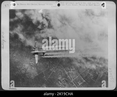 Un Boeing B-17 Forteresse volante des États-Unis Eighth Air Force passe au-dessus du coeur de Berlin, la fumée des incendies ayant commencé dans la région de Tempelhof, une partie de la capitale, le 3 février 1945. C'était l'un des 1 000 avions qui ont déchargé 2 500 tonnes Banque D'Images