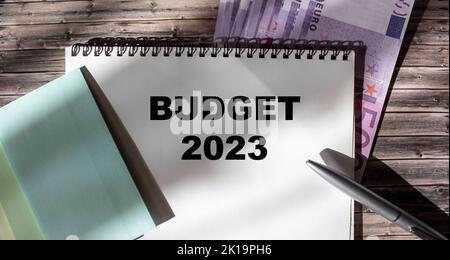 Budget 2023 message texte avec autocollants, stylo et billets en euros sur fond de bois Banque D'Images