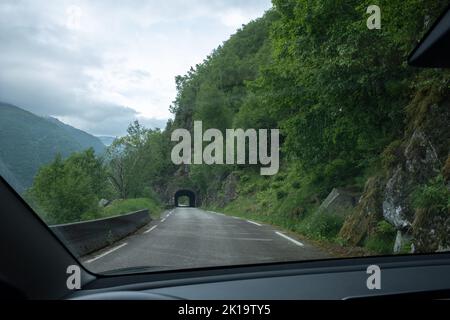 Kyrping, Norvège - 9 juin 2022: L'ancienne route du fjord d'Akra, POV d'un modèle Tesla 3 conduite sur la route pittoresque. Tunnel et ponts dans un ciel nuageux d Banque D'Images