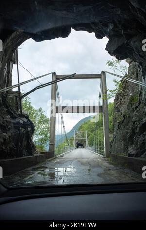 Kyrping, Norvège - 9 juin 2022: L'ancienne route du fjord d'Akra, POV d'un modèle Tesla 3 conduite sur la route pittoresque. Tunnel et ponts dans un ciel nuageux d Banque D'Images