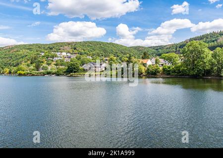 Quelques maisons au bord du lac Rursee, au milieu du parc national de l'Eifel, entouré par un paysage naturel unique et une nature préservée Banque D'Images