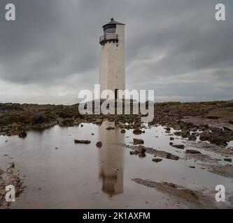 Vue sur le phare historique de la Southerness en Écosse avec réflexions dans les bassins de marée en premier plan Banque D'Images