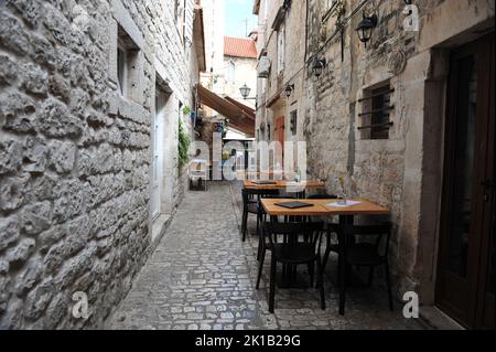 Petit restaurant dans une ruelle arrière isolée à Trogir, Croatie. Tableaux vides avec fleurs et menus. Personne. Banque D'Images