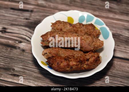 Cuisine arabe nourriture traditionnelle boeuf Kofta, kebab et la tarb kofta qui est la viande hachée enveloppée dans de la graisse d'agneau au charbon de bois grillé et servi sur plat profond, Banque D'Images