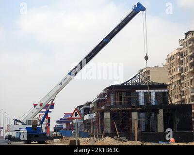 Le Caire, l'Egypte, le 25 août 2022: Un camion de grue mobile sur un site de construction d'un nouvel axe Shinzo Abe en Egypte se levant dans un nouveau bâtiment fait sur le JAPA Banque D'Images