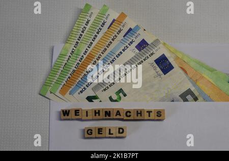 le mot allemand pour le bonus de noël avec des briques de wodden et des billets de banque en euros Banque D'Images