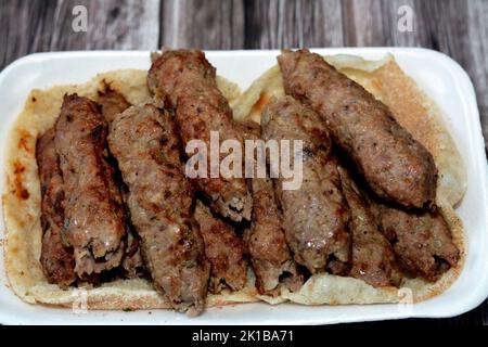 Cuisine arabe nourriture traditionnelle boeuf Kofta, kebab et la tarb kofta qui est la viande hachée enveloppée dans la graisse d'agneau au charbon de bois grillé et servi sur le pain plat, o Banque D'Images