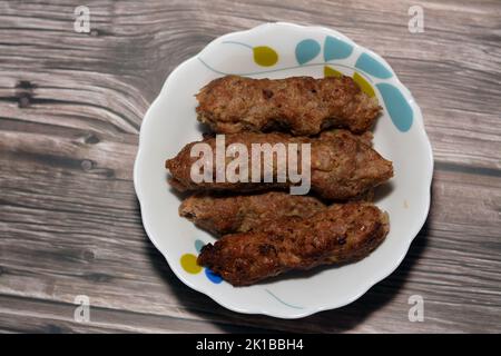 Cuisine arabe nourriture traditionnelle boeuf Kofta, kebab et la tarb kofta qui est la viande hachée enveloppée dans de la graisse d'agneau au charbon de bois grillé et servi sur plat profond, Banque D'Images