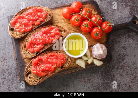 Catalans Pan con Tomate pain grillé espagnol frotté avec de l'ail frais et des tomates mûres, puis arrosé d'huile d'olive sur le panneau en bois du Banque D'Images