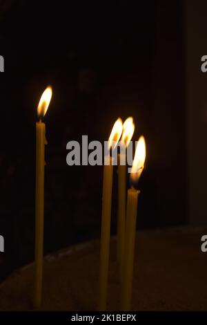 Bougies allumées dans l'église. De nombreuses bougies allumées sur fond sombre. Faible profondeur de champ. Banque D'Images