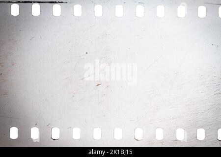 Texture ou surface poussiéreuse et rugueuse du film 35 mm.Film perforé rayé isolé sur fond blanc. Banque D'Images