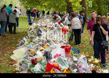 Les gens qui lisent des messages avec des fleurs dans Green Park à la suite du décès de la reine Elizabeth II Bouquets avec emballage en plastique disposés dans le parc Banque D'Images