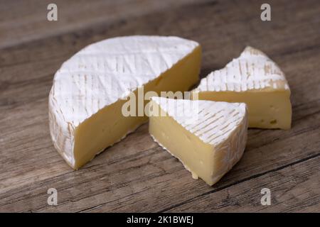 Fromage Brie rond avec une section découpée sur fond de bois, vue rapprochée. Banque D'Images