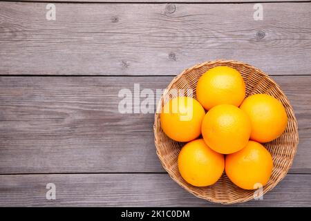 Fresh orange fruit in basket on a grey wooden background Stock Photo