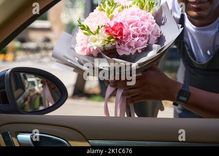 Guy tient un bouquet de fleurs à la voiture Banque D'Images