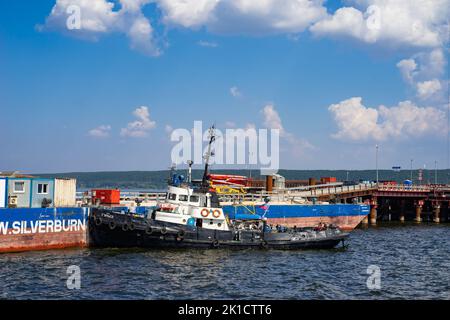 Tatarstan, Russie. 26 août 2022. Le remorqueur est amarré autour de la barge. Le bateau à remorqueurs coloré travaille sur un chantier de construction. Manœuvres près d'une barge Banque D'Images