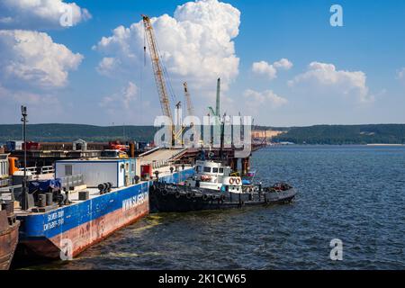 Tatarstan, Russie. 26 août 2022. Le remorqueur est amarré autour de la barge. Le bateau à remorqueurs coloré travaille sur un chantier de construction. Manœuvres près d'une barge Banque D'Images