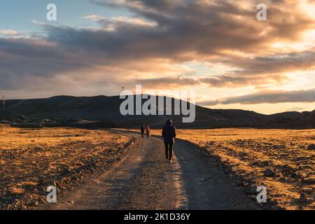 Expédition de touristes trekking sur route de terre parmi la zone volcanique au coucher du soleil à l'Islande Banque D'Images