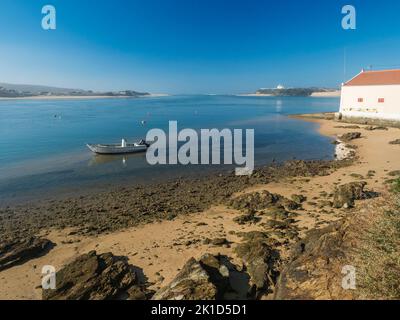 Vue idyllique de l'embouchure de la rivière Mira qui coule dans l'océan Atlantique avec petite maison de plage et bateau de pêche ancré. Vila Nova de Milfontes Banque D'Images