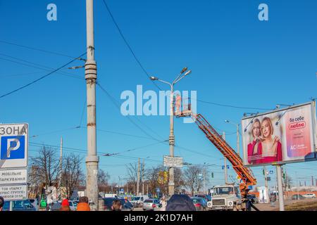 Dnipro, Ukraine - 02.15.2022: Un travailleur municipal en équipement de protection effectue des travaux dangereux pour éliminer une interruption du réseau électrique. Banque D'Images