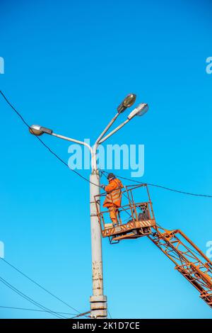 Dnipro, Ukraine - 02.15.2022: Un travailleur municipal en équipement de protection effectue des travaux dangereux pour éliminer une interruption du réseau électrique. Banque D'Images