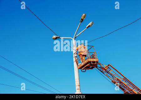 Un travailleur municipal en équipement de protection effectue des travaux dangereux pour éliminer une interruption du réseau électrique. Un employé répare une lampe de rue de Banque D'Images