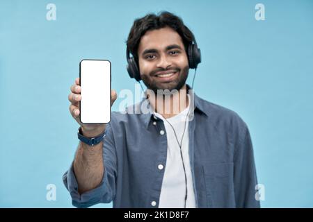 Un homme arabe heureux montrant un écran de maquette de téléphone portable isolé sur bleu. Banque D'Images