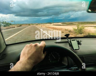 Conduite sous le ciel orageux du coucher du soleil. Vue de l'intérieur de la voiture Banque D'Images