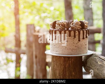 Beau gâteau rond avec chocolat et biscuits sur bois rond Banque D'Images