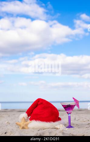 Fond de Noël chapeau de Père Noël sur la plage avec étoile de mer et cocktail Banque D'Images