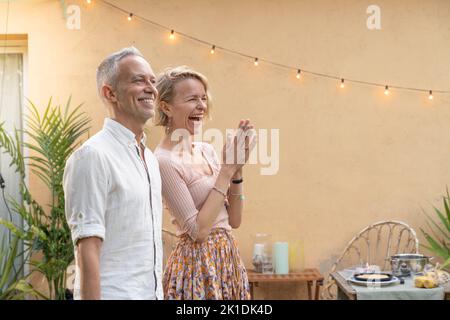 Heureux mature couple attrayant attendant leurs invités à la fête dans le patio. Banque D'Images