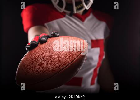 Homme dans un joueur de football américain tenue de balle vers la caméra. Banque D'Images