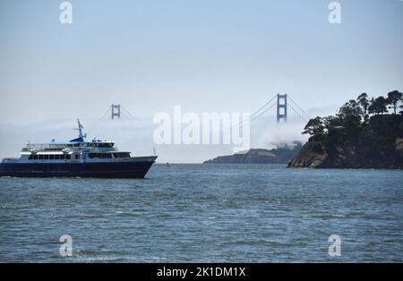 Panorama grand format du pont du Golden Gate couvert de brouillard avec un ferry de San Francisco arrivant à Tiburon en premier plan. Banque D'Images